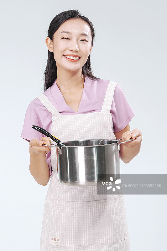 做饭的年轻女人拿着汤锅图片素材