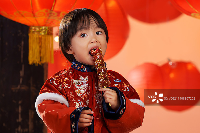 可爱的小男孩拿着糖葫芦庆新年图片素材
