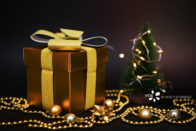 罗马尼亚阿拉德，黑色背景上有小球和珠子的小圣诞树上的金色礼物图片素材