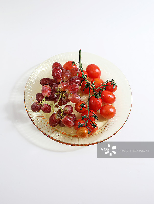 白色桌面碟子上装着的新鲜水果西红柿图片素材