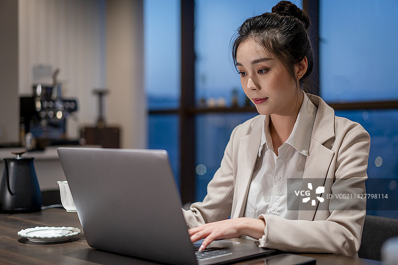 一个亚洲年轻女性在夜晚的办公室加班图片素材