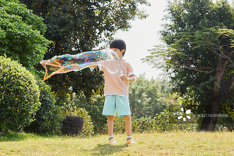 在户外草坪上玩泡泡的小男孩图片素材