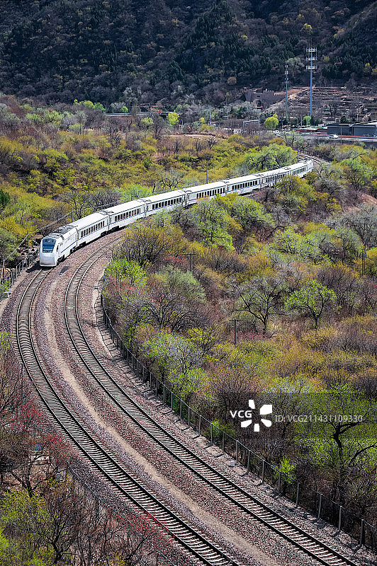 居庸关山谷里，一辆列车行驶在蜿蜒的铁路上图片素材