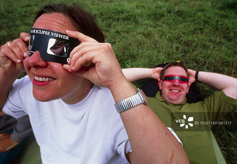 一名女子戴着防护眼镜观看日食图片素材