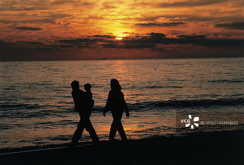 夕阳在海滩上映出一家人的剪影图片素材