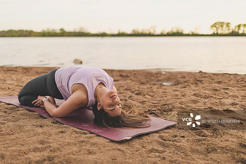 在美国密苏里州克雷夫科尔湖海滩上做瑜伽的女性伸展运动图片素材