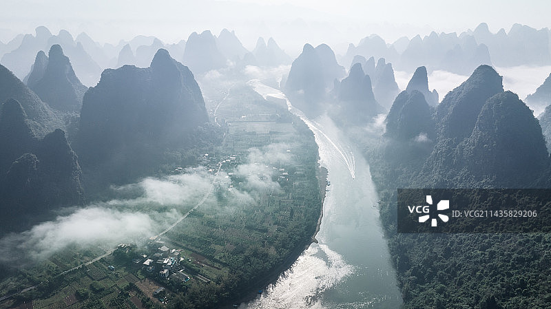 早晨阳光下桂林漓江峡谷中的云雾和水面上的竹筏图片素材