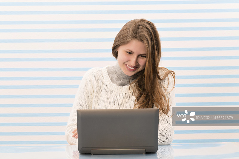 女人在用笔记本电脑，微笑着图片素材