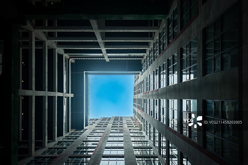 从苏州昆山花桥游站未来城富有未来感的建筑内部仰望天空，好似一条隧道的尽头是蓝天白云图片素材