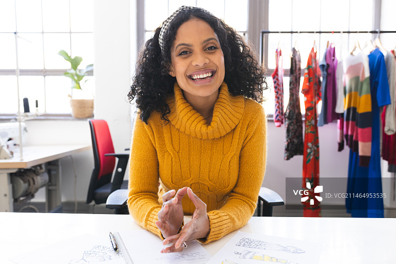 快乐的混血女时装设计师在工作室的办公桌前进行视频通话和大笑图片素材