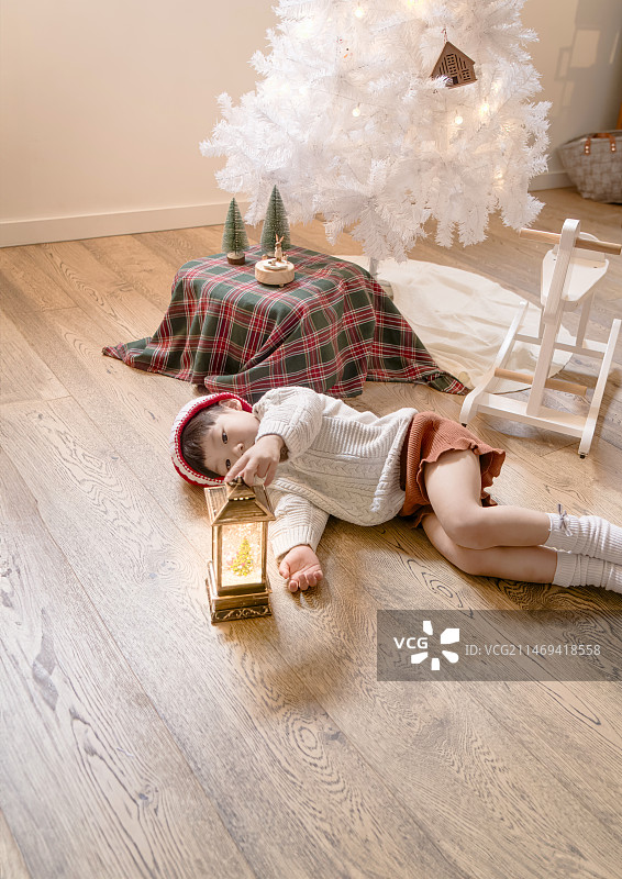 圣诞宝贝躺在地板上看漂亮的圣诞音乐盒灯图片素材