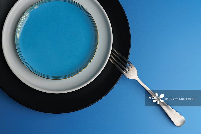 蓝色背景下的盘子和叉子餐具特写镜头图片素材