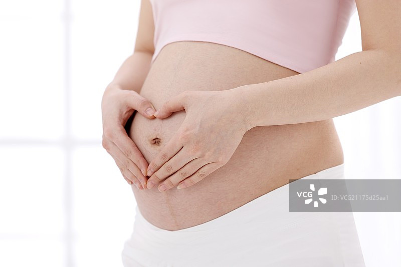 孕妇在肚子上做心形手势图片素材