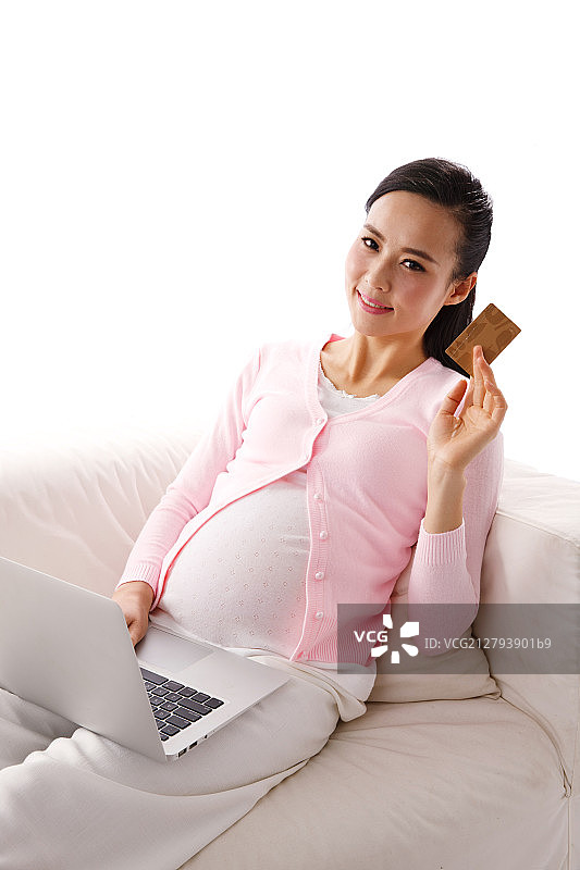孕妇坐在沙发上网上购物图片素材