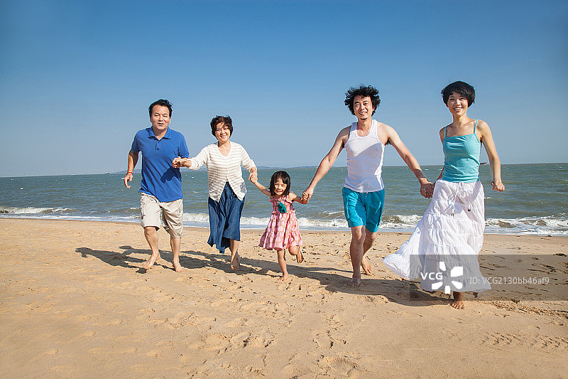 东方家庭手牵手在沙滩上奔跑图片素材