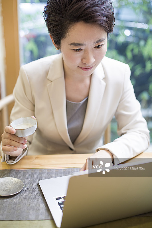 商务女性在茶馆使用笔记本电脑工作图片素材