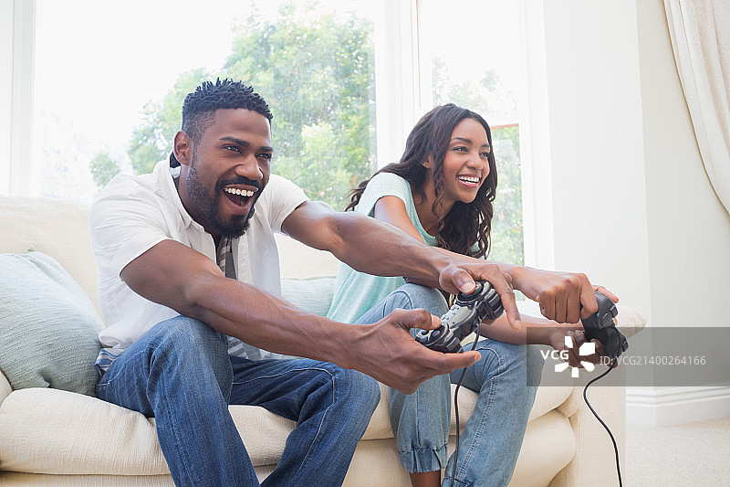 幸福的夫妇在沙发上玩视频游戏在家里的客厅图片素材