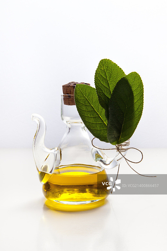 橄榄油在一个小玻璃瓶和鼠尾草叶图片素材