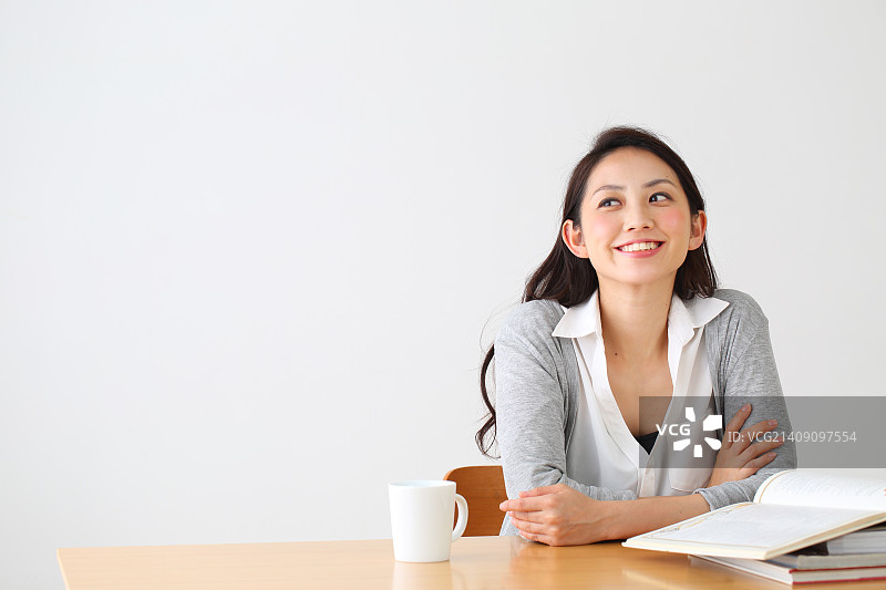 迷人的日本女人坐在一张桌子在一个通风的房间图片素材