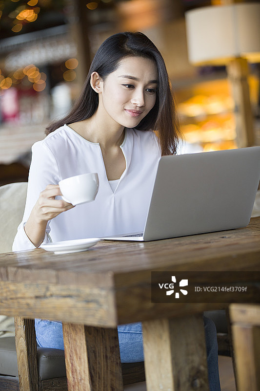年轻女子在咖啡馆使用笔记本电脑图片素材