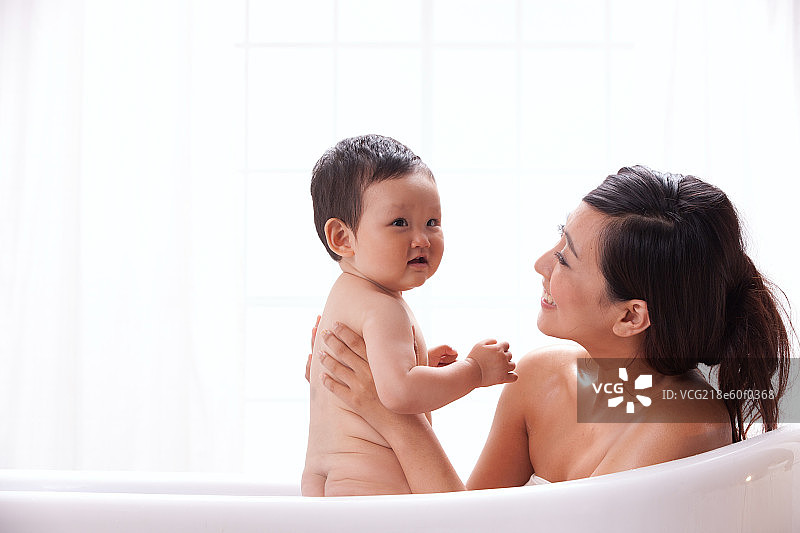 母亲和婴儿坐在浴缸中洗澡图片素材