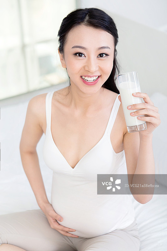 坐在床上喝牛奶的孕妇图片素材