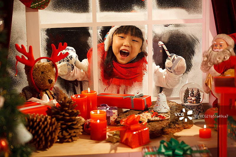 小女孩透过窗户看圣诞节礼物图片素材