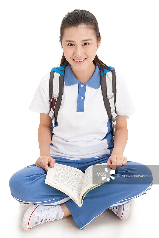 一个盘着腿坐的中学女生拿着书图片素材