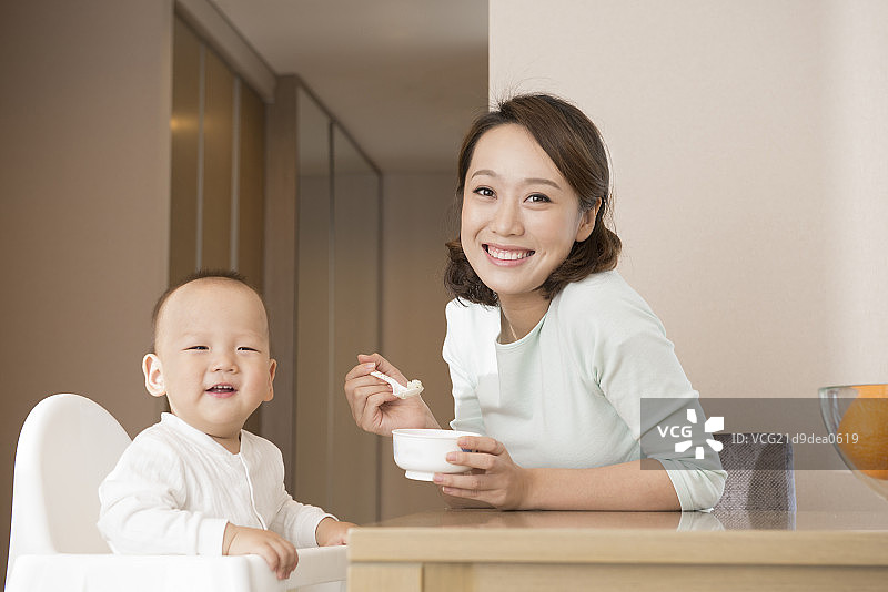 Young mother feeding baby boy图片素材