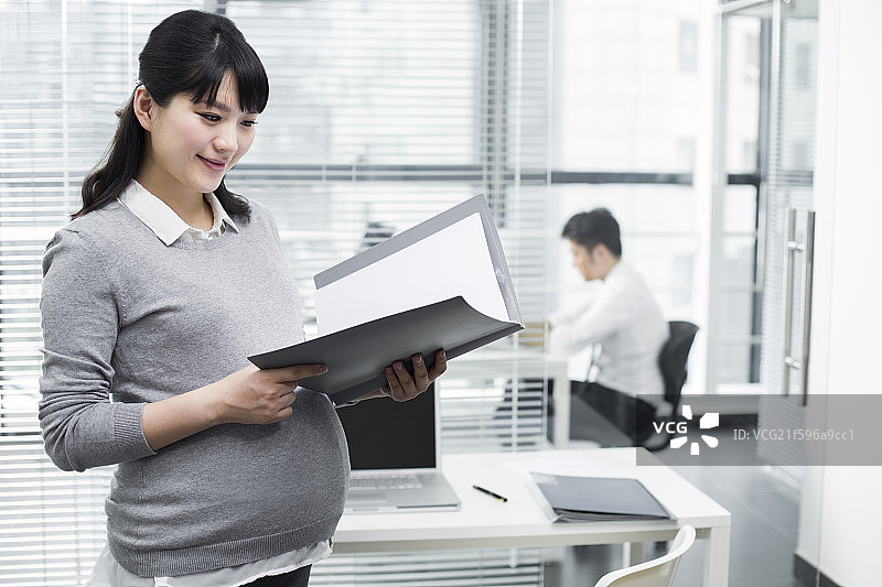 怀孕的商务女士拿着文件夹图片素材