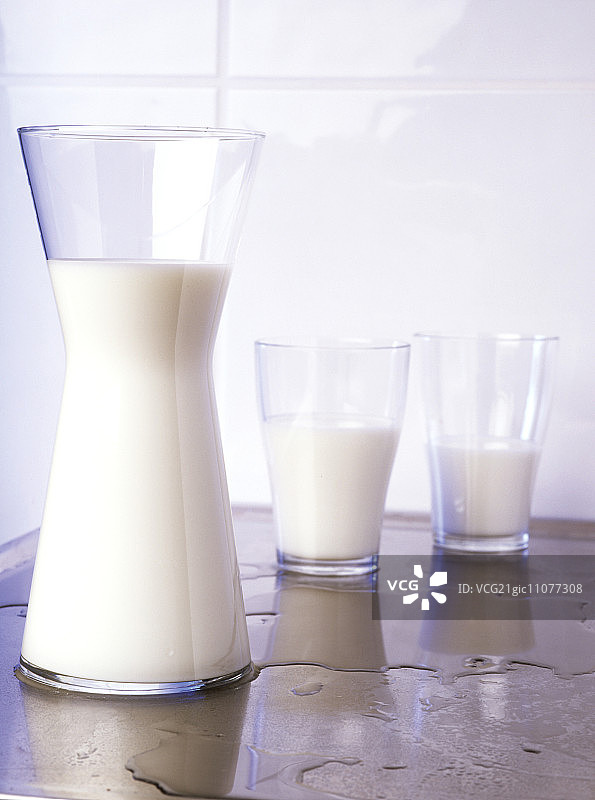 牛奶装在两个玻璃杯和玻璃罐子里图片素材