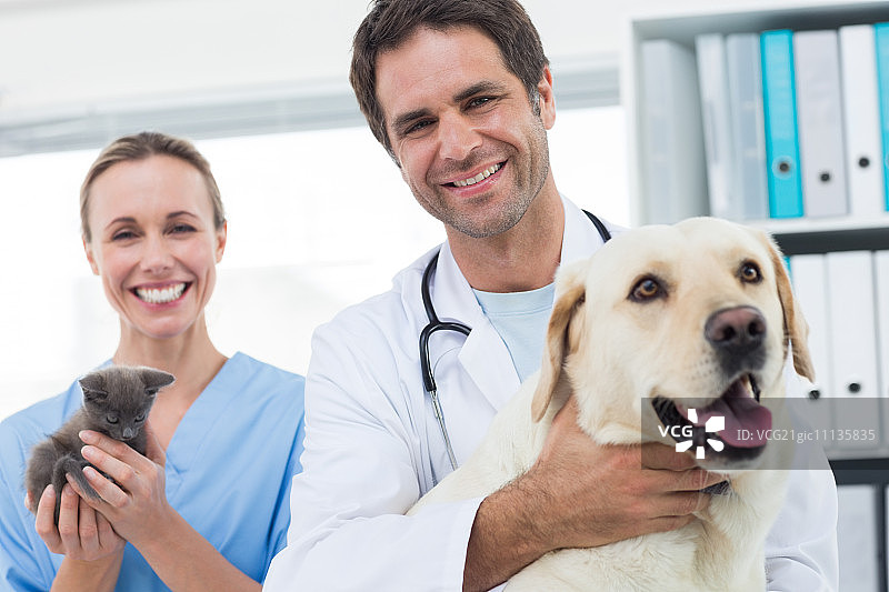 自信的兽医与狗和小猫在医院的肖像图片素材
