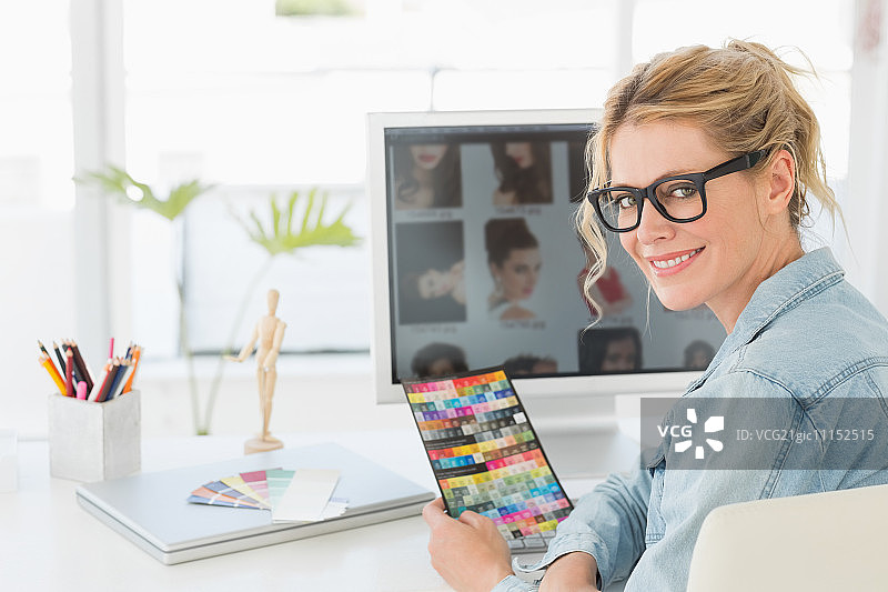 金发设计师拿着彩色图表在她的办公桌微笑在相机在创意办公室图片素材