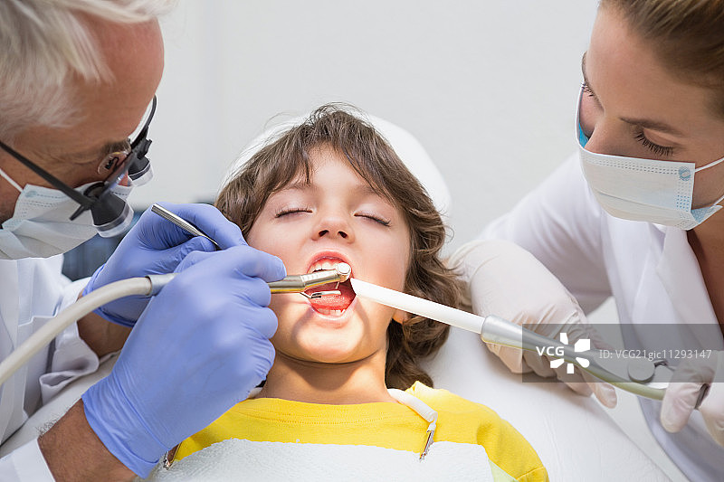 儿科牙医和助手在牙科诊所检查一个小男孩的牙齿图片素材