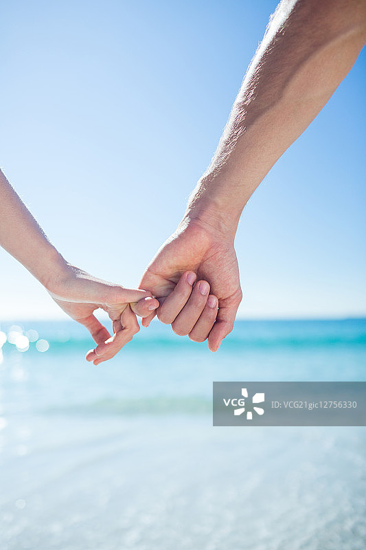 一对情侣在海滩上手牵手散步图片素材