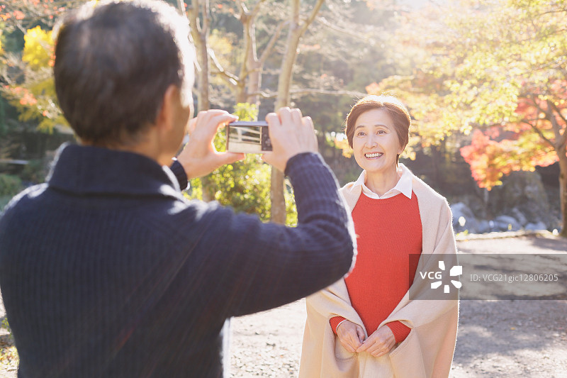 秋天，一对日本老年夫妇在一个传统公园里拍照图片素材