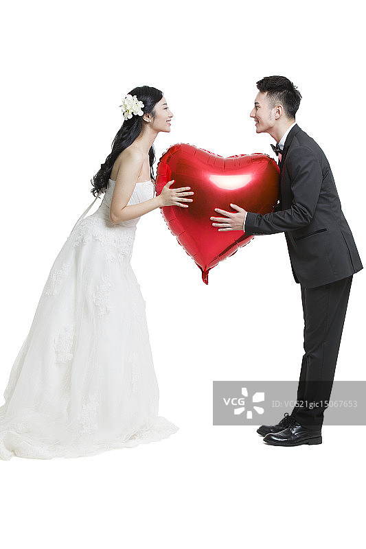 快乐的新娘和新郎拿着一个心型气球图片素材