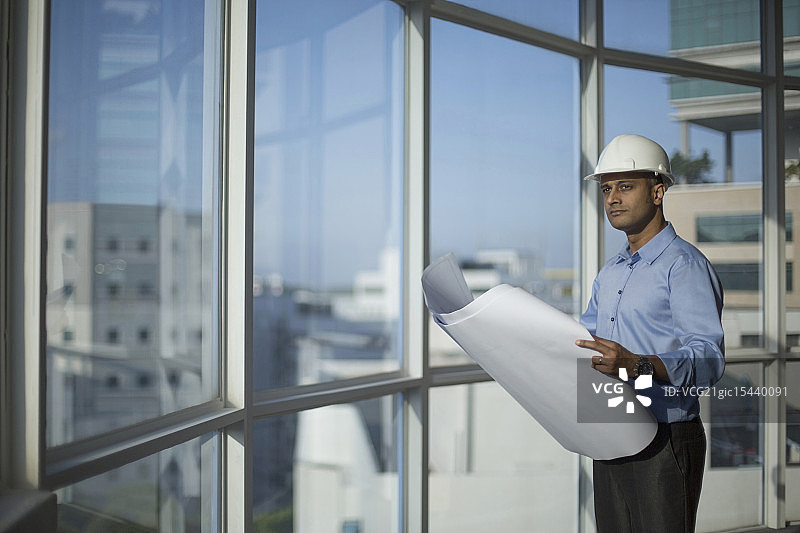 新加坡，男建筑师，戴安全帽，透过窗户看建筑平面图图片素材