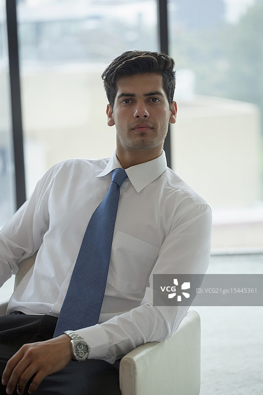 印度，一个打着蓝领领带的男人坐在办公室的椅子上图片素材