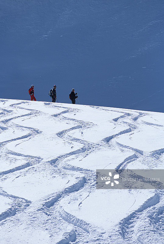 三个滑雪者和之字形滑雪道在雪图片素材