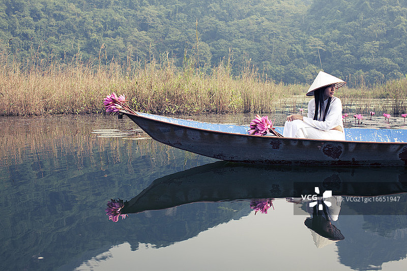 穿着传统服饰坐船旅行的越南妇女图片素材