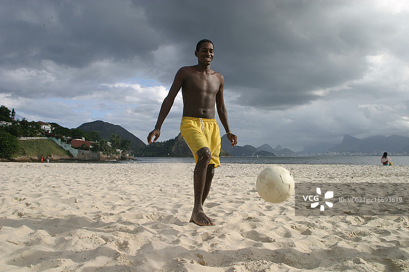年轻人在沙滩上踢足球图片素材