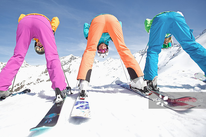 三个年轻的女滑雪者透过她们的腿看着照相机图片素材