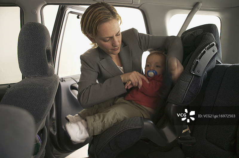 母亲把婴儿扣在汽车座椅上图片素材