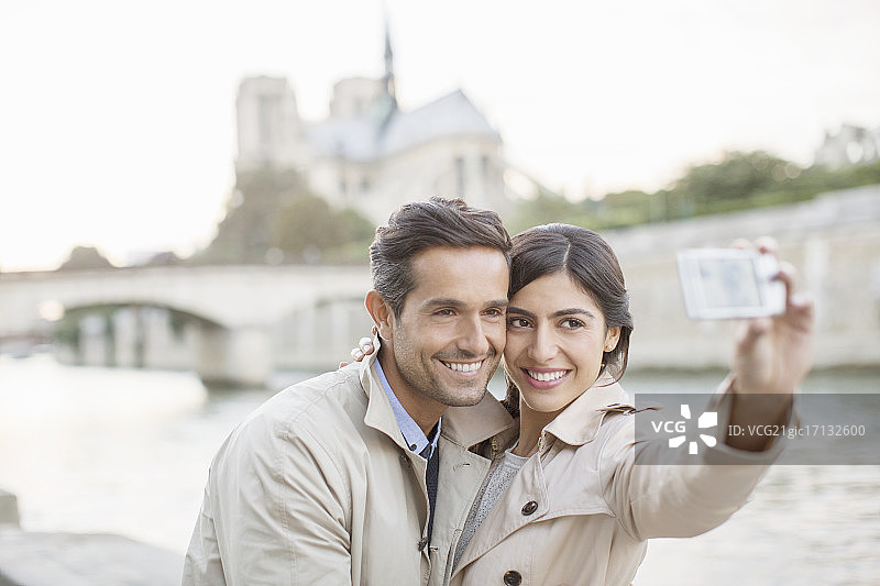 一对情侣在巴黎圣母院附近的塞纳河上自拍图片素材