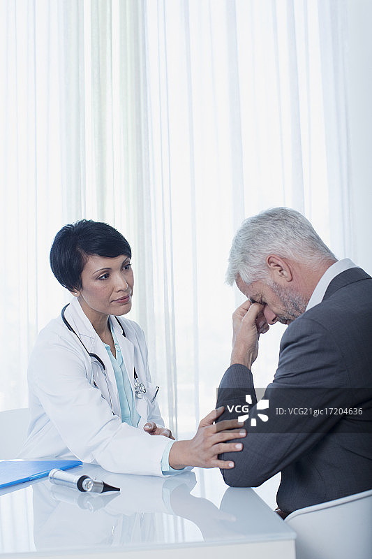 女医生坐在桌子上安慰悲伤的病人图片素材