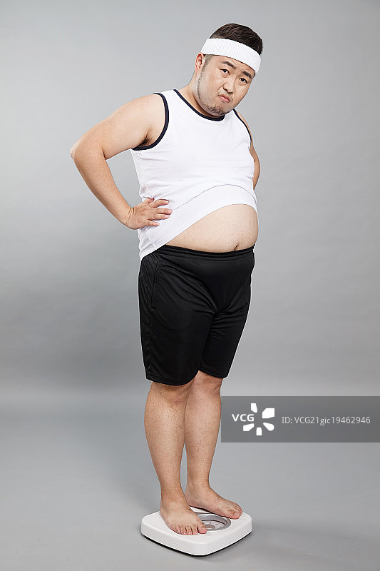 肥胖的青年男人称体重图片素材