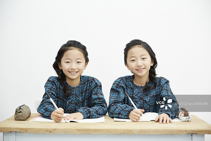 一对双胞胎姐妹在桌子上微笑图片素材