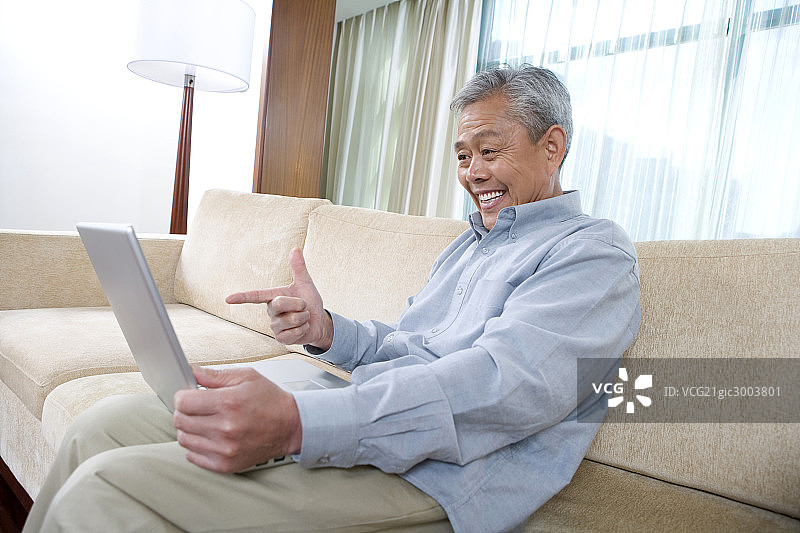 老年人在沙发上用笔记本电脑上网图片素材