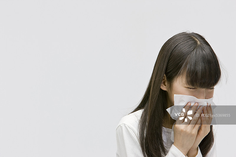 年轻女孩用纸巾擤鼻子图片素材